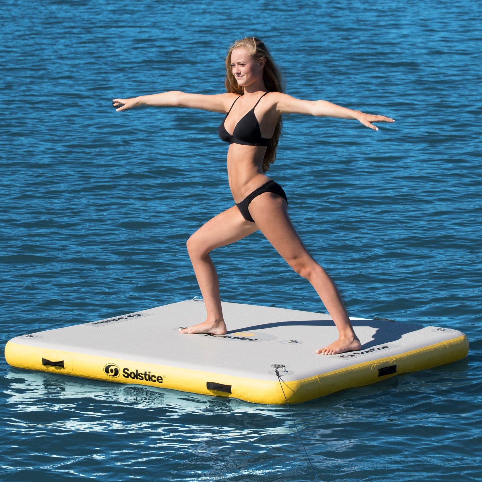 Person practicing yoga on a Solstice Classic inflatable floating dock on calm lake water